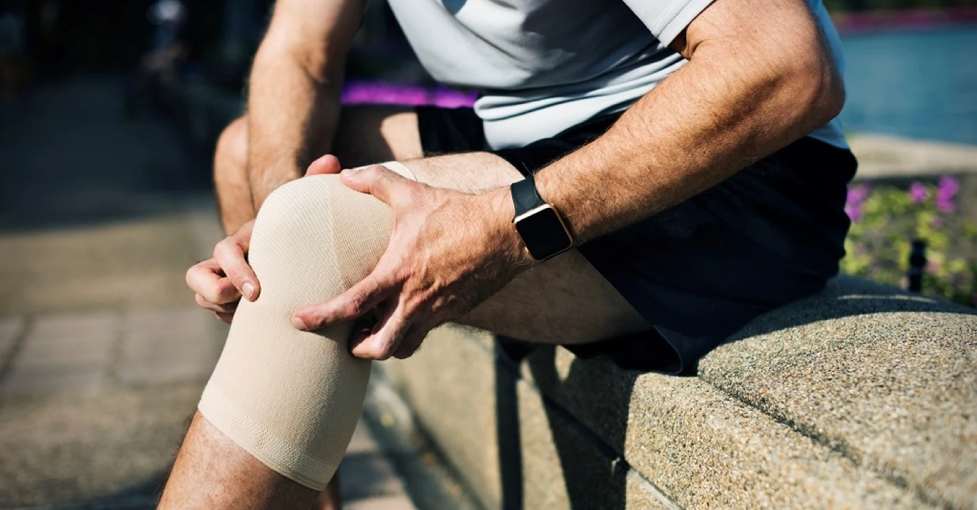 Man holding his knee, wearing a knee sleeve