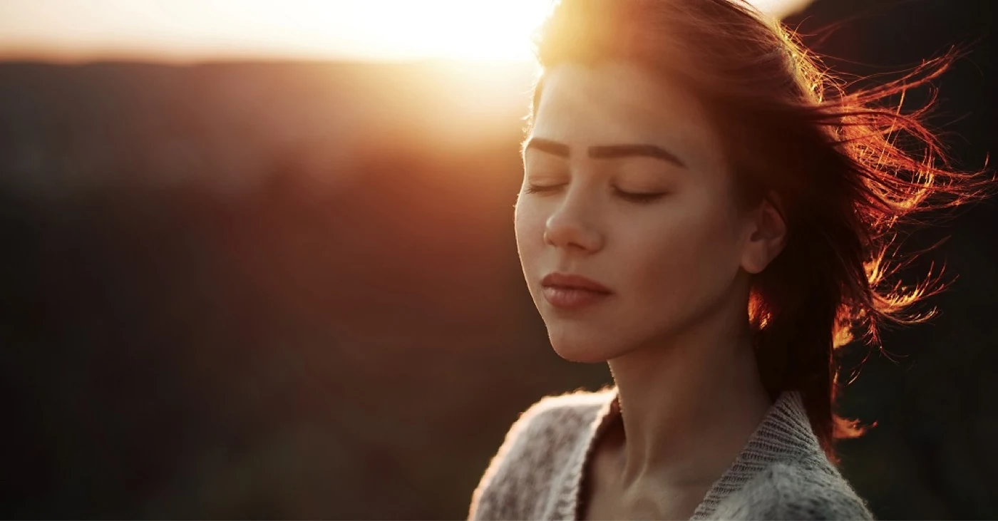 Woman with her eyes closed outdoors at sunset